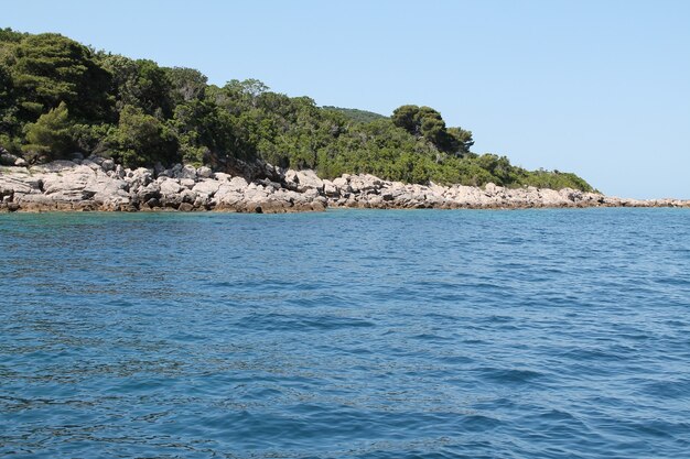 Colpo di paesaggio di una collina verde nell'acqua blu con un cielo blu chiaro