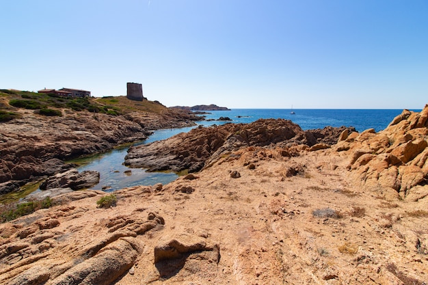 Colpo di paesaggio di una spiaggia con grandi rocce sulla collina in un cielo blu chiaro