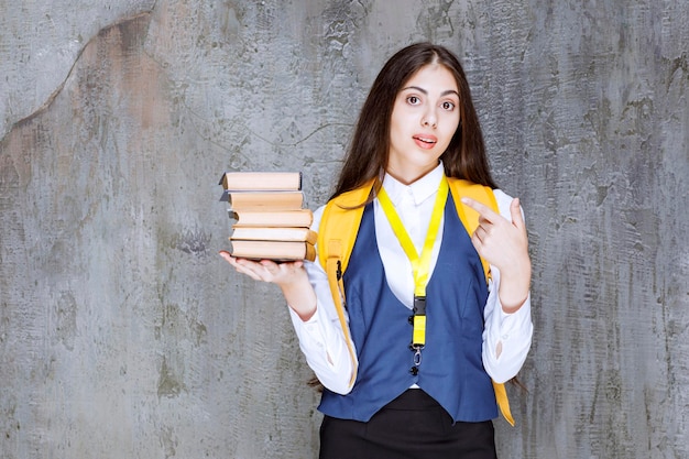 Colpo di studentessa dai capelli lunghi con libri in piedi. Foto di alta qualità