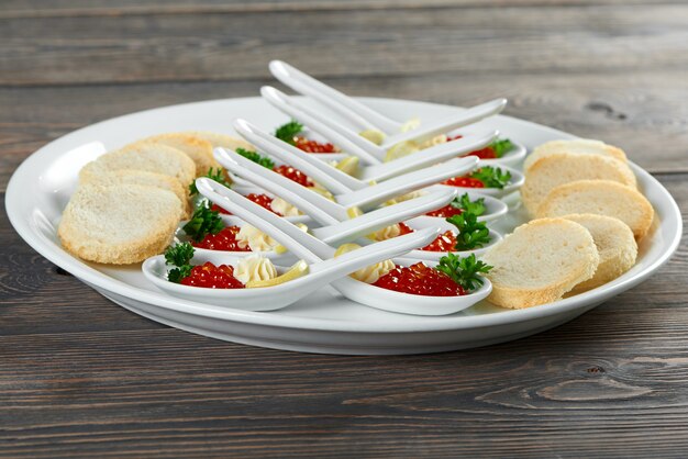 Colpo di un piatto con caciar rosso servito in cucchiai collocati vicino croccante fette biscottate delicatezza mangiare cibo gourmet porzione di menu ristorante frutti di mare servizio di decorazione di lusso cafe piatto concetto.