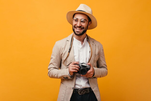 Colpo di uomo con cappello a tesa larga che tiene la fotocamera su sfondo isolato