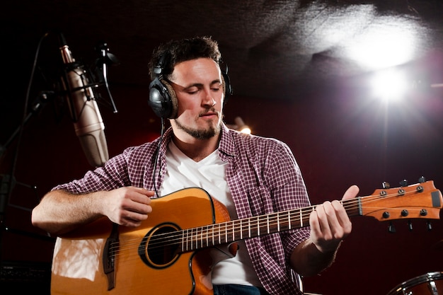 Colpo di vista bassa di un uomo che suona la chitarra e che indossa le cuffie