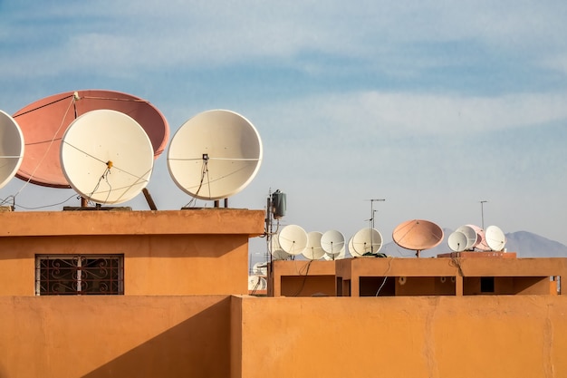 Colpo grandangolare di antenne paraboliche bianche sul tetto di un edificio