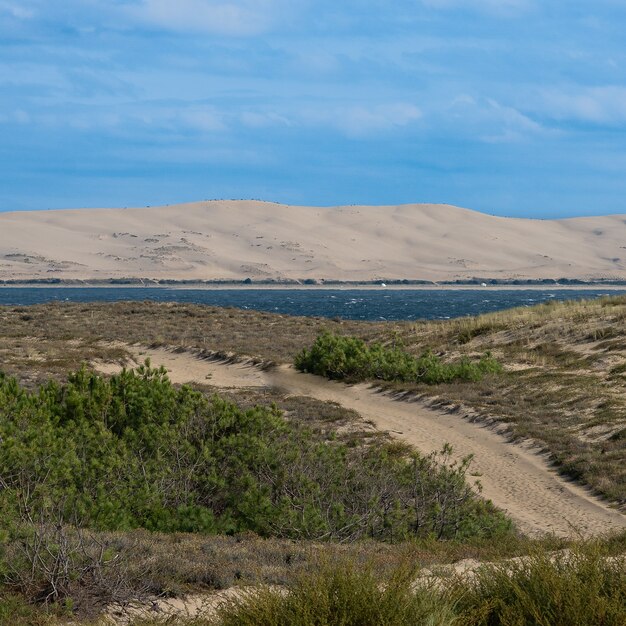 Colpo grandangolare di una strada che si estende nell'acqua circondata da montagne sotto un cielo blu