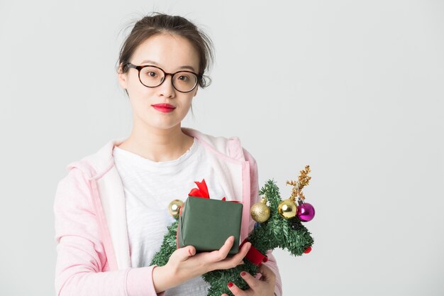 Colpo in studio della giovane donna asiatica con un regalo di Natale