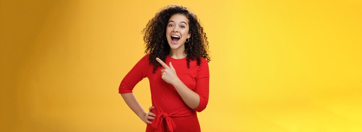 Foto gratuito colpo in vita di bella ragazza caucasica divertita e colpita con i capelli ricci in vestito rosso mout aperto