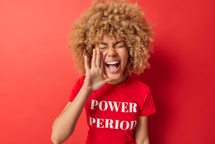 Foto gratuito colpo in vita di giovane donna dai capelli ricci tiene il palmo vicino alla bocca urla ad alta voce grida notizie indossa una maglietta casual con iscrizione isolata su sfondo rosso vivido concetto di persone ed emozioni