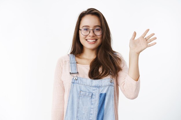 Colpo in vita di una simpatica ragazza principiante che saluta con speranza un nuovo collega, facendo amici sorridenti amichevoli e felici alla telecamera mentre alza il palmo in un gesto di saluto