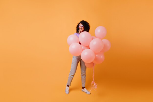 Colpo integrale della donna africana allegra che prepara per la festa. ragazza nera pensierosa in attesa di un evento.