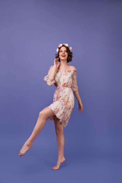 Colpo integrale di meravigliosa ragazza in abito estivo. Giovane donna ben vestita in cerchietto di fiori che ballano.