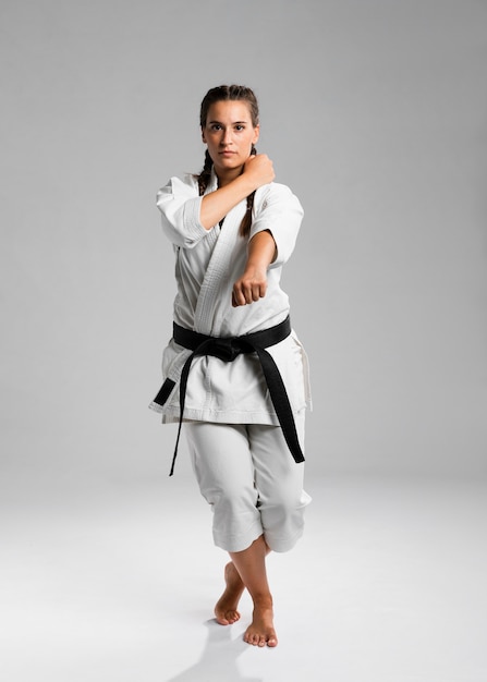 Colpo integrale di una donna con cintura nera e kimono praticando il karate