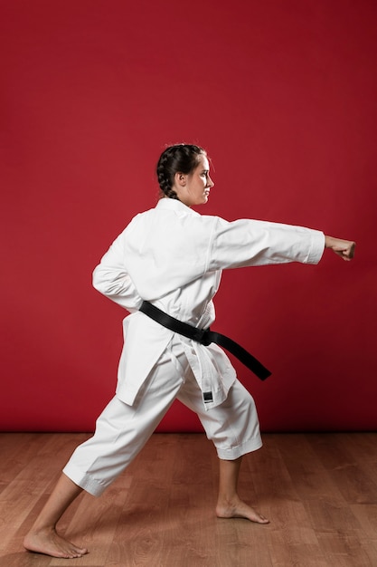 Colpo integrale di una donna con cintura nera e kimono praticando il karate