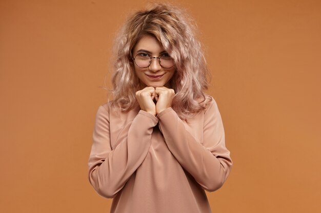 Colpo isolato di splendida affascinante giovane femmina con capelli rosati e sorriso carino sensazione di timidezza