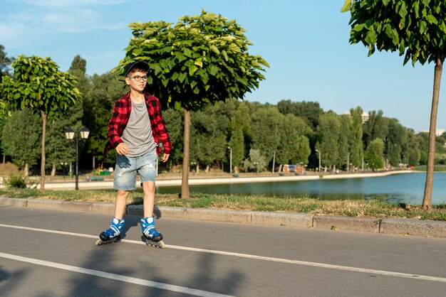 Colpo lungo del ragazzo con pattini in linea blu