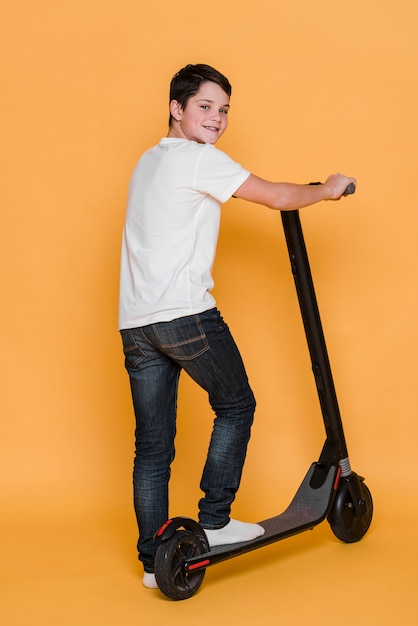 Colpo lungo del ragazzo con scooter