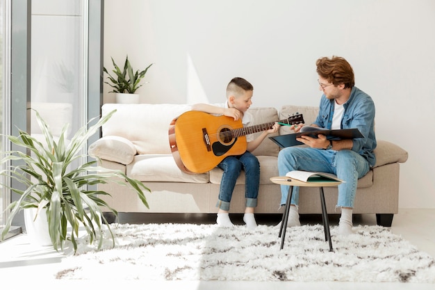 Colpo lungo dell'insegnante e del ragazzo a suonare la chitarra