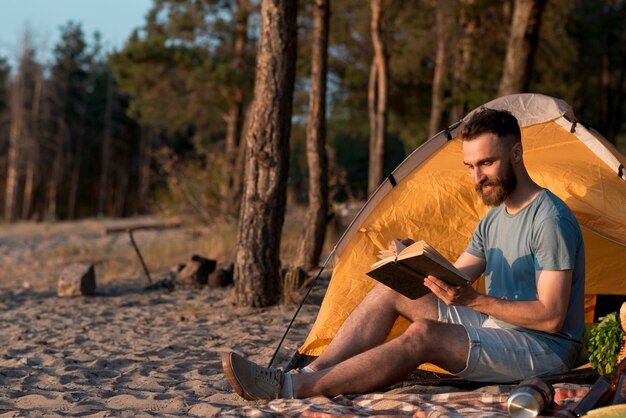 Colpo lungo dell&#39;uomo che legge un libro dalla tenda