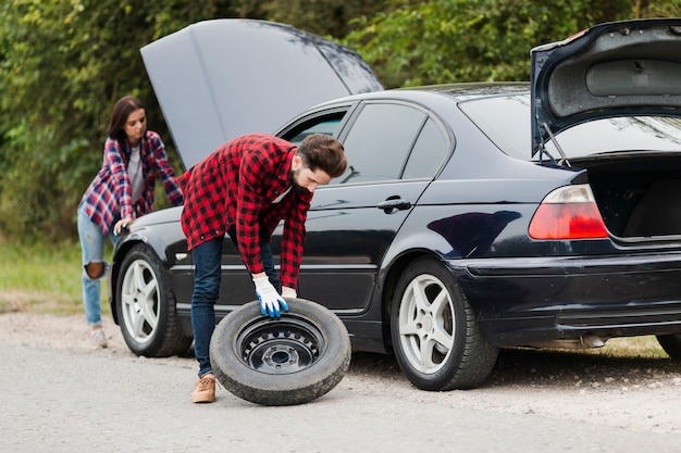 Colpo lungo delle coppie che riparano automobile