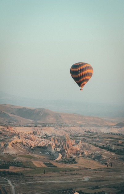 Colpo lungo di una mongolfiera multicolore che galleggia nel cielo in alto sopra le montagne