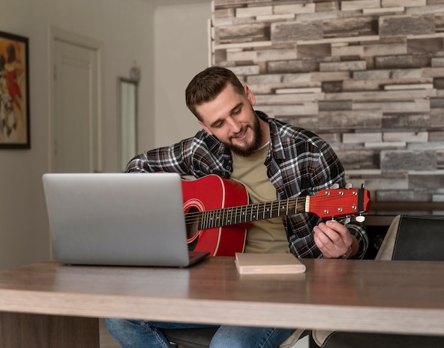 Colpo medio della chitarra di sintonizzazione dell'uomo