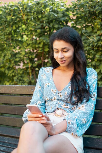 Colpo medio della donna che esamina il suo telefono