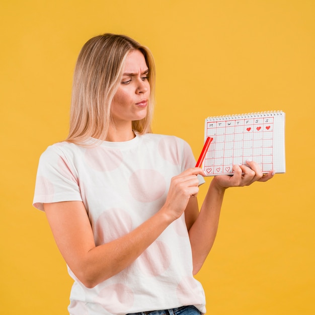 Colpo medio della donna che mostra il calendario periodo