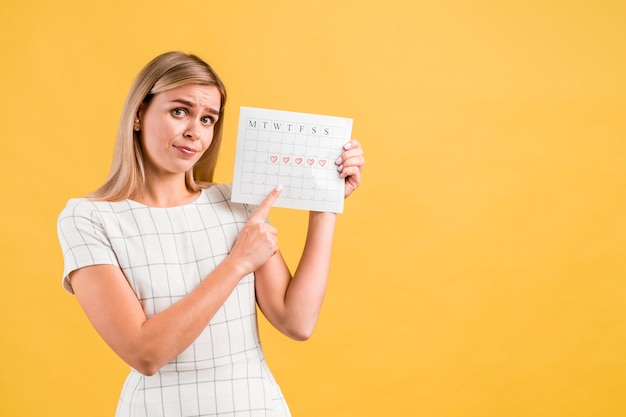 Colpo medio della donna che mostra il calendario periodo