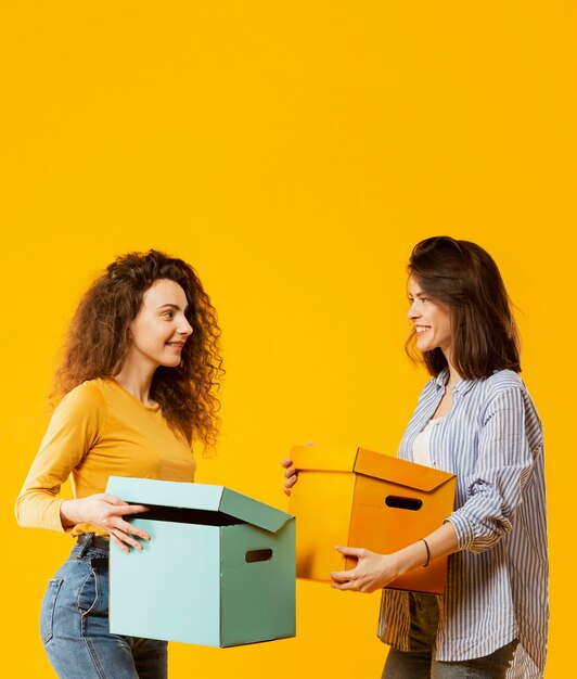 Colpo medio delle donne che trasportano scatole