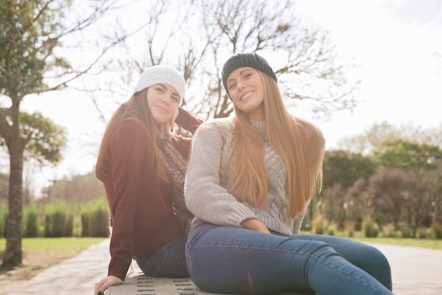 Colpo medio di due donne sorridenti che si siedono su un banco