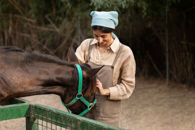 Colpo medio donna che accarezza cavallo