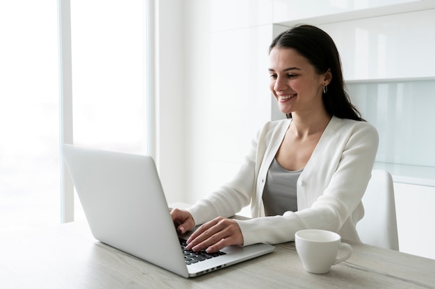 Colpo medio donna che lavora al computer portatile