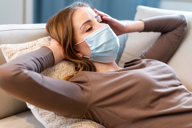 Colpo medio donna con maschera stare sul divano