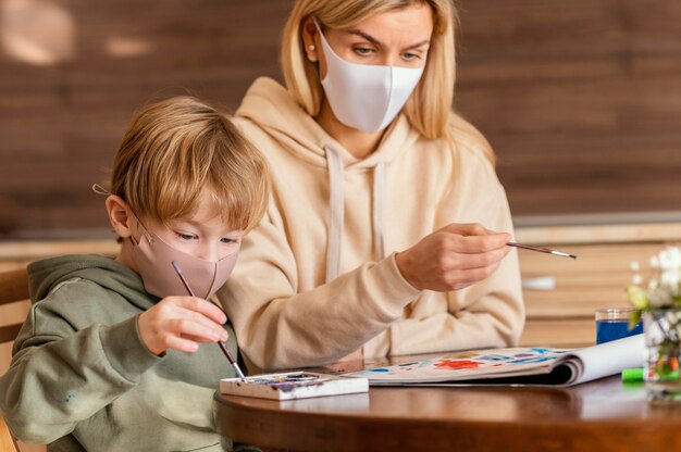 Colpo medio donna e bambino che tengono i pennelli