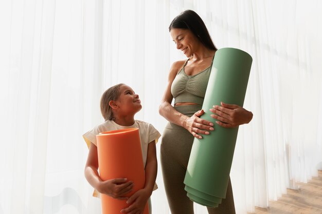 Colpo medio donna e bambino con tappetino da yoga