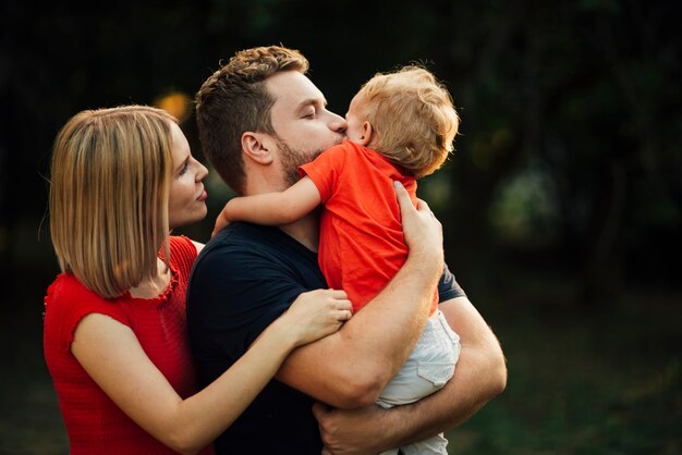 Colpo medio famiglia felice che bacia il loro figlio