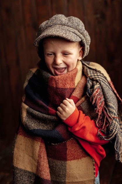 Colpo medio ragazzo felice con cappello e sciarpa