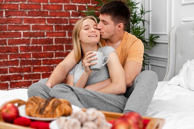 Colpo medio uomo che bacia la donna con la tazza