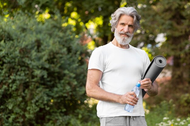 Colpo medio uomo con tappetino yoga e acqua