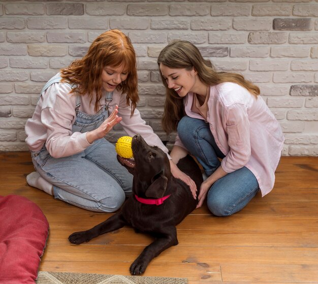 Colpo pieno donne felici e cane sul pavimento