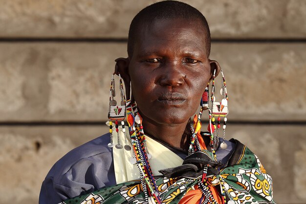 Colpo poco profondo del fuoco di un maschio africano con i grandi orecchini mentre esamina la macchina fotografica