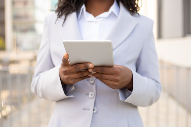 Colpo potato della donna di affari afroamericana che per mezzo della compressa. Mani femminili che tengono dispositivo digitale moderno. Concetto di tecnologia