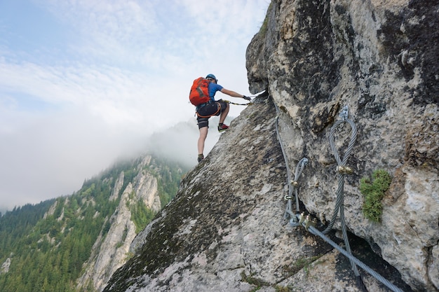 Colpo sbalorditivo di un giovane che si arrampica su una scogliera in una giornata fredda e nebbiosa