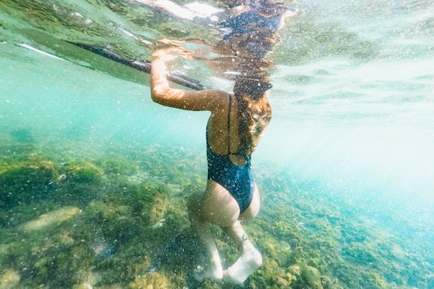 Colpo subacqueo di donna con tavola da surf