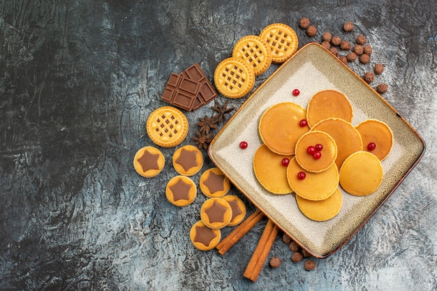 Colpo superiore di deliziosi pancake rotondi con deliziosi dolci su grigio