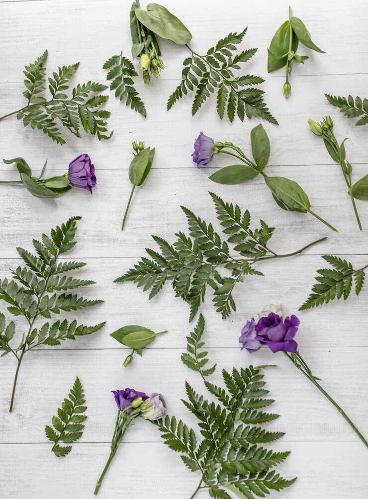 Foto gratuito colpo verticale ad alto angolo di fiori viola lisianthus e foglie verdi su una superficie di legno