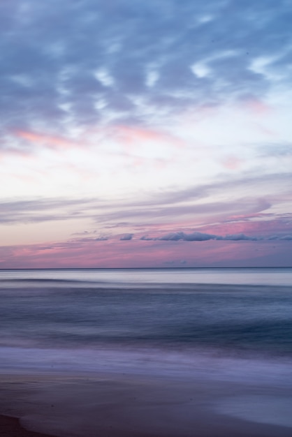 Colpo verticale del bellissimo cielo colorato sul mare durante l'alba