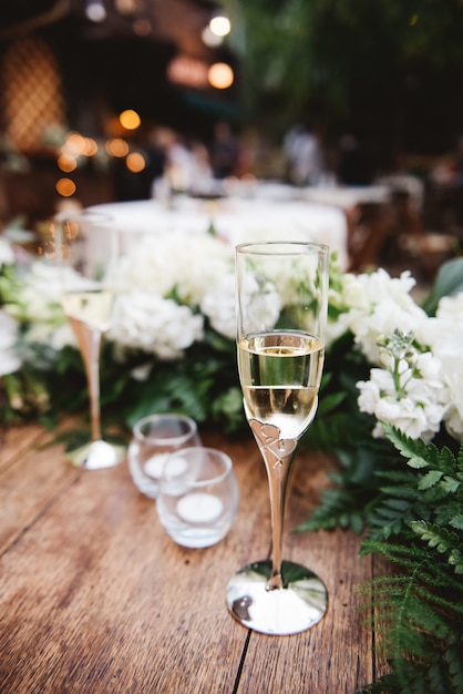 Colpo verticale del fuoco selettivo di un bicchiere di champagne su una superficie di legno a un matrimonio