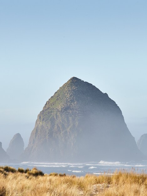 Colpo verticale del Haystack Rock nella nebbia mattutina a Cannon Beach, Oregon