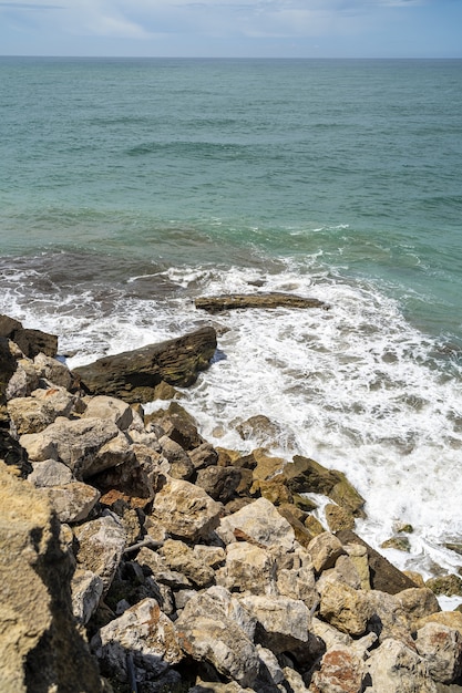 Colpo verticale del mare circondato dalle rocce sotto la luce del sole durante il giorno