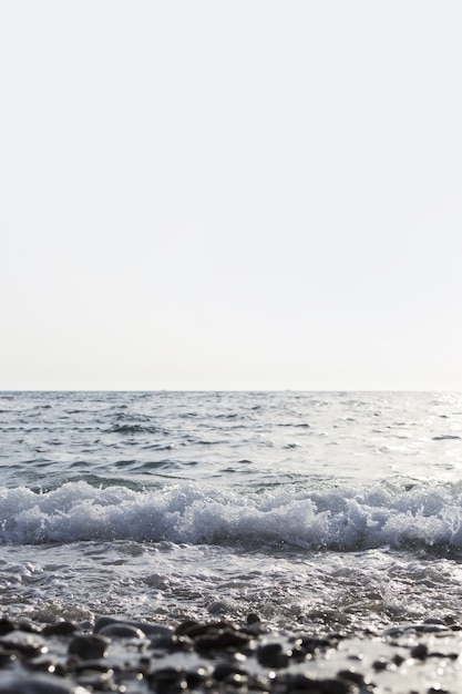 Colpo verticale del mare con belle onde e chiaro cielo bianco